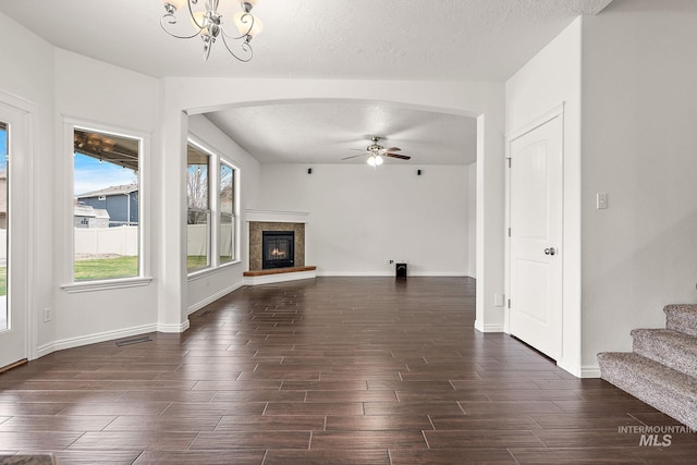 1452 E Pistioa, Meridian, ID 83642 - unfurnished living room with arched walkways, ceiling fan with notable chandelier, dark wood finished floors, and visible vents