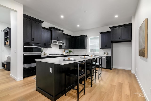 8709 W Pickett Creek St, Star, ID 83669 - kitchen featuring dark cabinets, under cabinet range hood, dishwasher, light wood-style floors, and recessed lighting