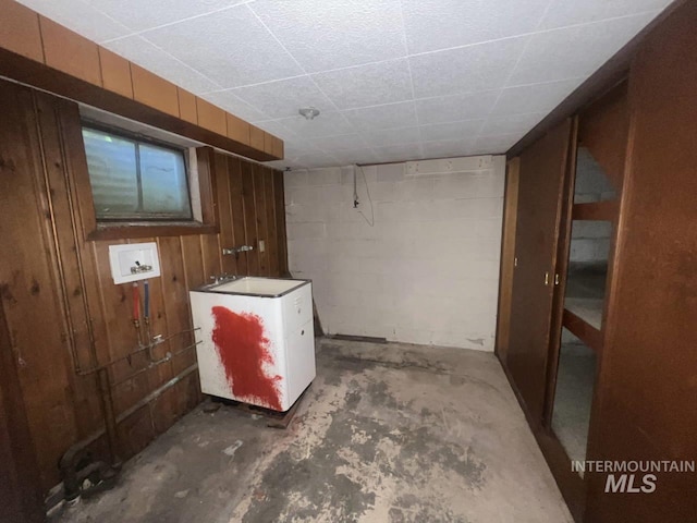 basement with wood walls and white fridge