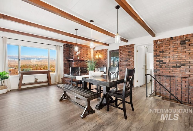 dining room featuring hardwood / wood-style flooring, brick wall, and beamed ceiling