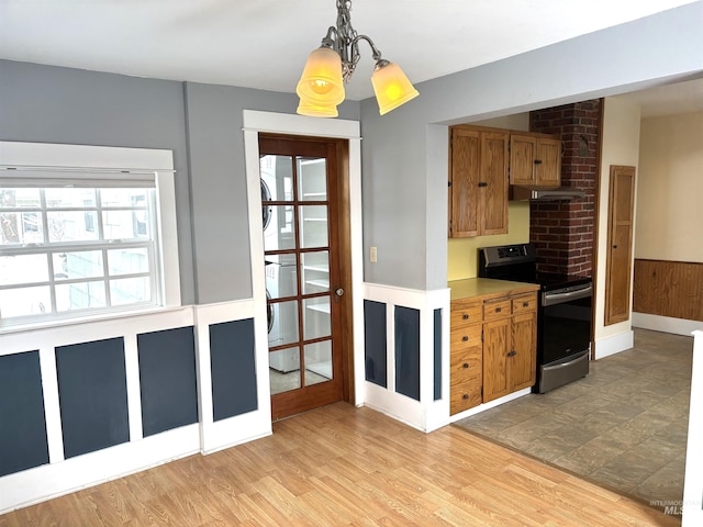 616 E 8th, Moscow, ID 83843 - kitchen with stainless steel electric stove, a chandelier, brown cabinetry, under cabinet range hood, and pendant lighting