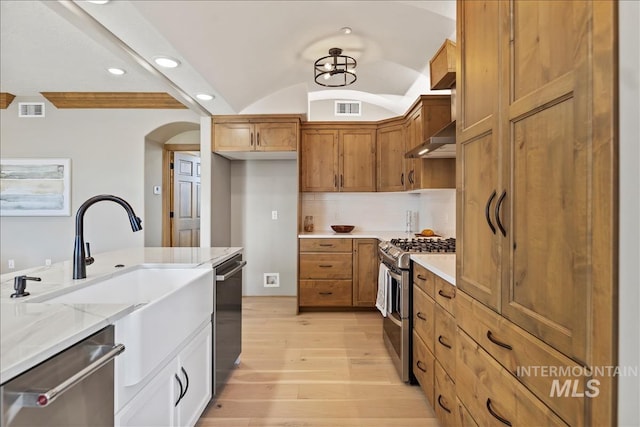 79 E Aikens Rd, Apt Eagle, ID 83616 - kitchen featuring stainless steel appliances, light wood-style flooring, arched walkways, lofted ceiling, and light stone countertops