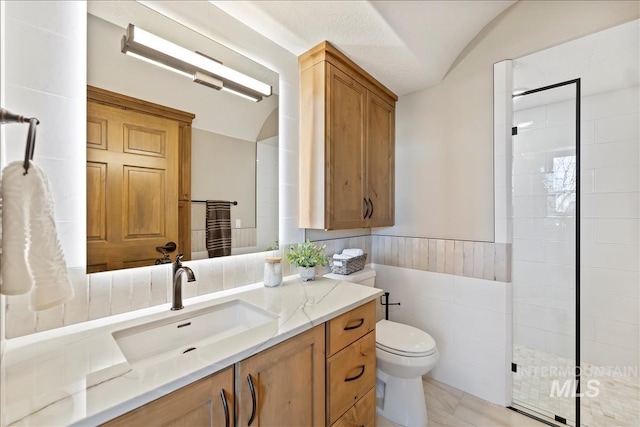 79 E Aikens Rd, Apt Eagle, ID 83616 - full bathroom with vanity, a tile shower, wainscoting, tile walls, and lofted ceiling