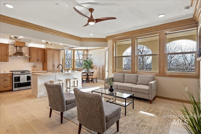 79 E Aikens Rd, Apt Eagle, ID 83616 - living area with ornamental molding, a ceiling fan, a textured ceiling, wainscoting, and light wood finished floors
