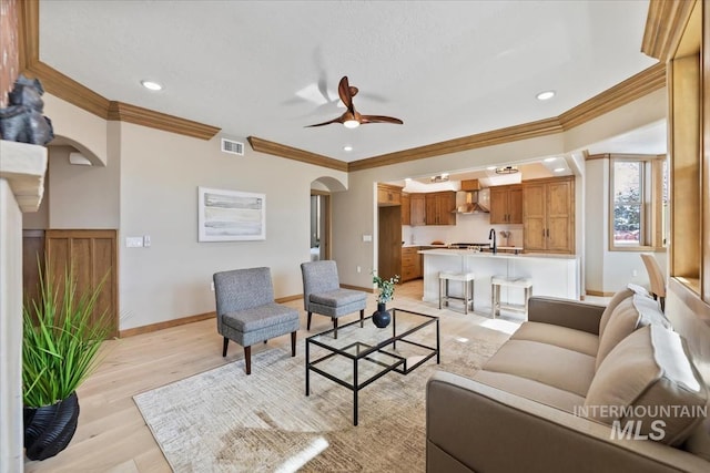 79 E Aikens Rd, Apt Eagle, ID 83616 - living area with arched walkways, light wood-style floors, a ceiling fan, crown molding, and recessed lighting