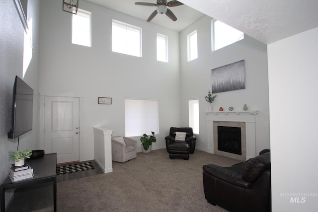 carpeted living room with ceiling fan, a fireplace, and baseboards