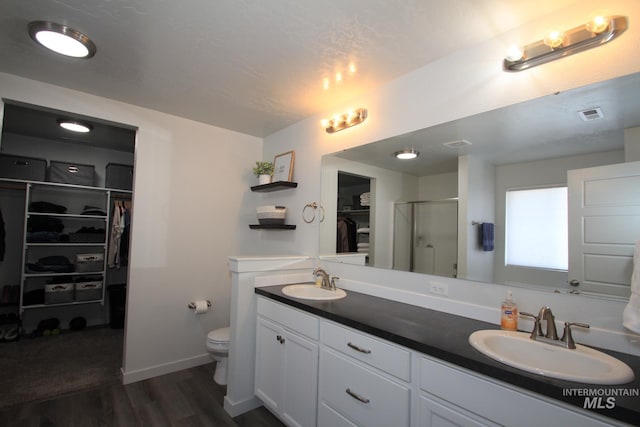 full bathroom featuring a sink, a shower stall, toilet, and wood finished floors