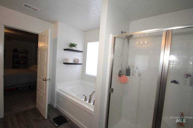 bathroom with visible vents, a garden tub, a shower stall, and wood finished floors