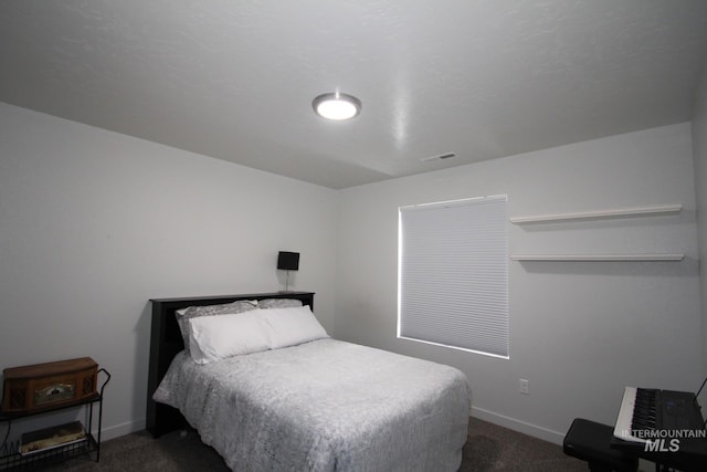 bedroom featuring baseboards, visible vents, and dark colored carpet