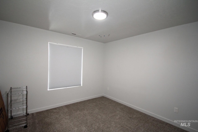 carpeted spare room featuring baseboards