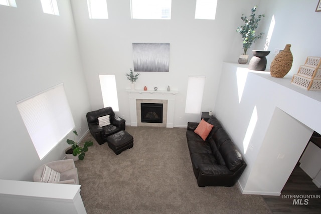 carpeted living area with a towering ceiling, a fireplace, and baseboards