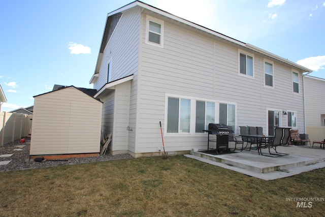 back of house featuring a patio area, fence, a lawn, and an outbuilding