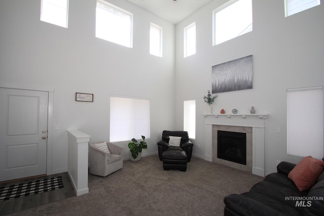 carpeted living room with a high ceiling, baseboards, and a tiled fireplace