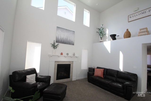 living area featuring a fireplace, carpet flooring, and a towering ceiling