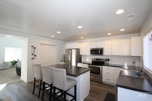 kitchen with dark countertops, visible vents, appliances with stainless steel finishes, and a sink