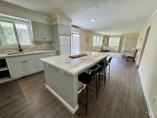 250 Hill Rd, Orofino, ID 83543 - kitchen featuring freestanding refrigerator, a breakfast bar area, a wall mounted air conditioner, dark wood-style flooring, and a sink