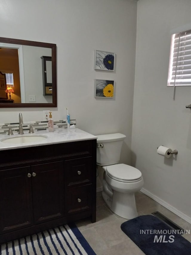 bathroom with tile patterned flooring, visible vents, baseboards, toilet, and vanity