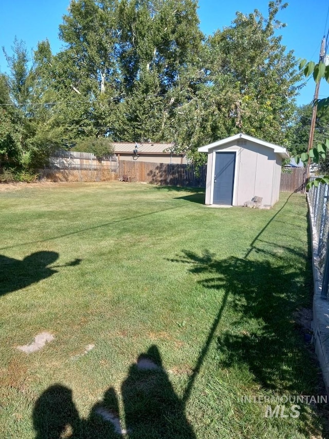 view of yard with an outbuilding, a fenced backyard, and a shed