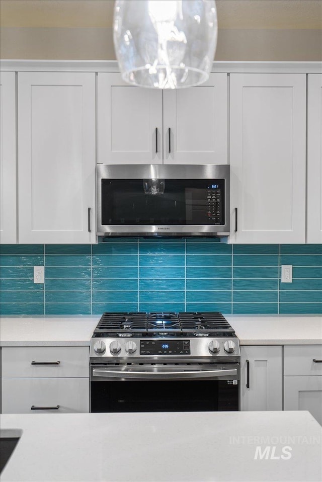 kitchen with backsplash, stainless steel appliances, and white cabinetry