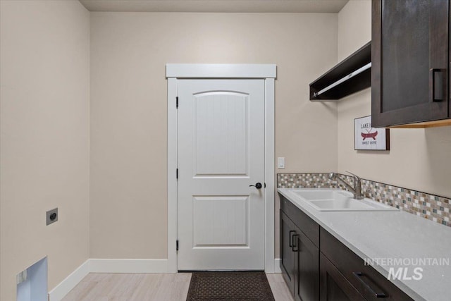 laundry room featuring electric dryer hookup, cabinets, and sink