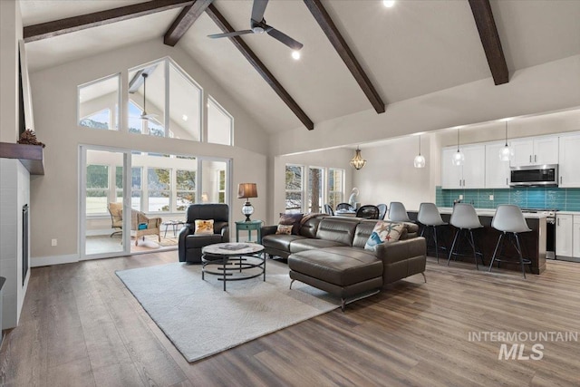 living room featuring hardwood / wood-style floors, ceiling fan with notable chandelier, beam ceiling, and high vaulted ceiling