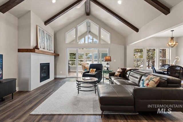 living room with dark hardwood / wood-style floors, a fireplace, high vaulted ceiling, and an inviting chandelier