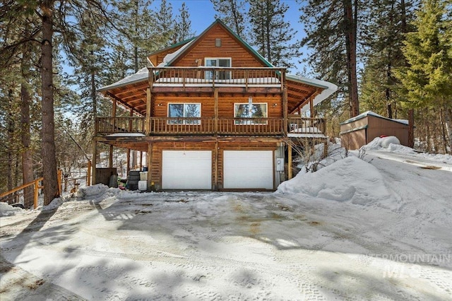 view of front of property featuring a garage, a wooden deck, a balcony, and faux log siding