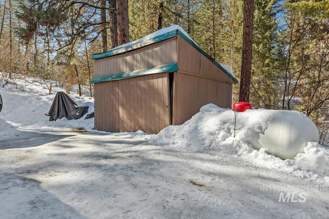 snow covered structure with an outbuilding