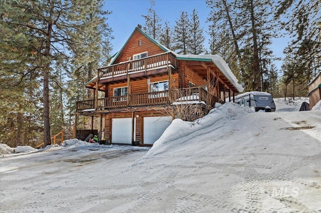 view of front of house with a deck, an attached garage, and faux log siding