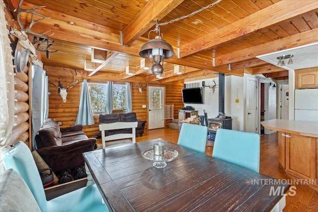 dining area featuring wood ceiling, beam ceiling, light wood finished floors, and a wood stove