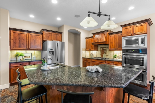 731 E Eaglewoods Ln, Eagle, ID 83616 - kitchen with stainless steel appliances, custom range hood, an island with sink, backsplash, and recessed lighting