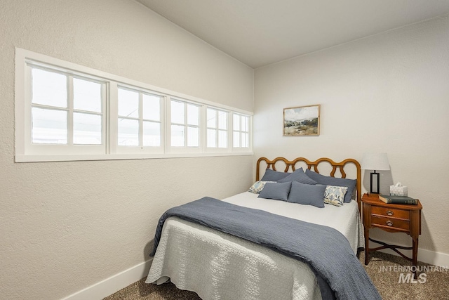 carpeted bedroom with baseboards and a textured wall