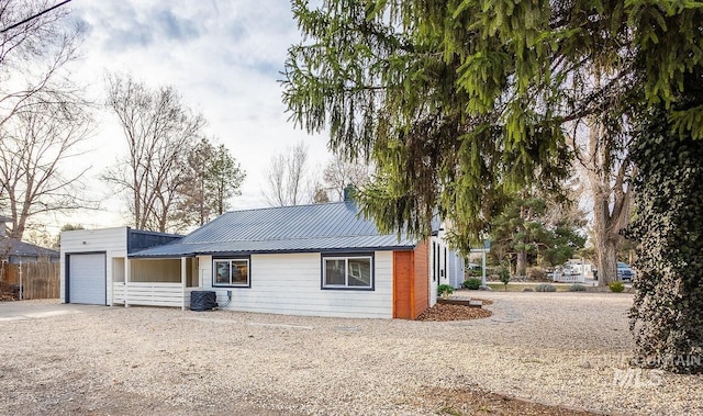 rear view of house with driveway, metal roof, and a garage