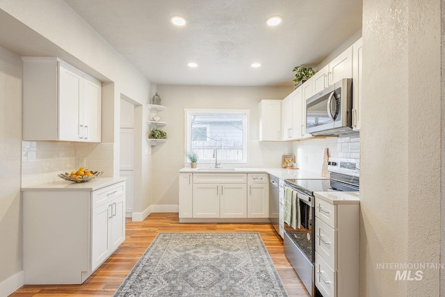 kitchen featuring a sink, stainless steel appliances, light wood-style flooring, and white cabinets