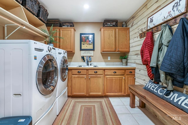 laundry room featuring cabinets, light tile patterned floors, washer and dryer, wooden walls, and sink