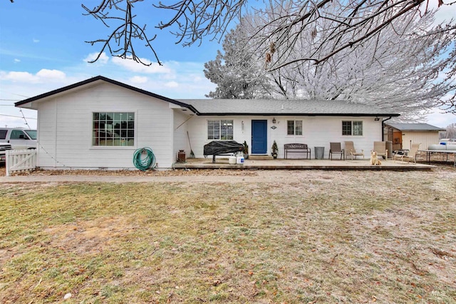 back of property with a lawn and a patio