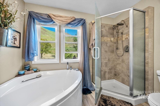 full bathroom featuring a bath, toilet, and a shower stall