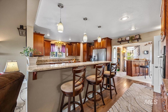 kitchen featuring light stone counters, a kitchen breakfast bar, stainless steel appliances, and a peninsula