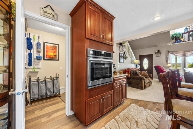 kitchen featuring oven, open floor plan, recessed lighting, light countertops, and light wood finished floors