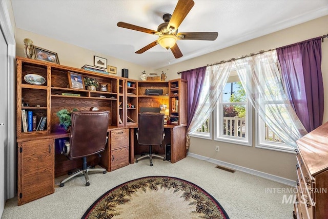 carpeted office featuring visible vents, a ceiling fan, and baseboards