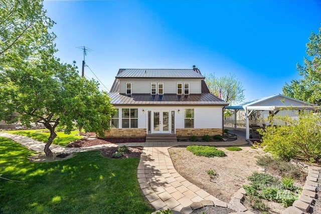 rear view of house with a yard, french doors, metal roof, and stone siding