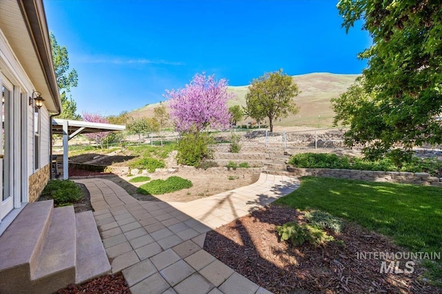 view of yard with fence, a mountain view, and a patio area