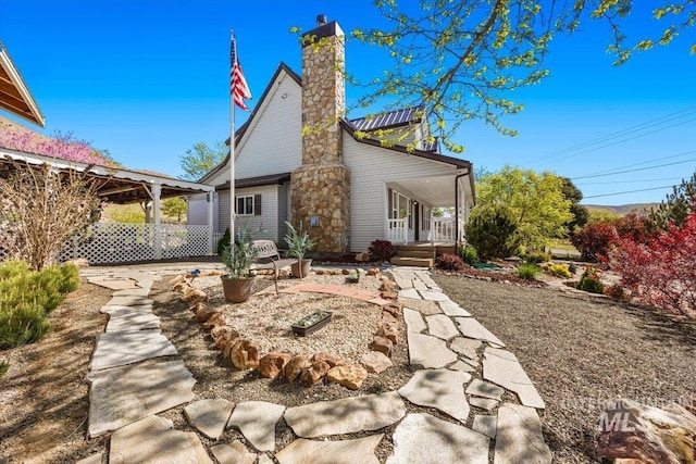 back of house featuring covered porch and a chimney