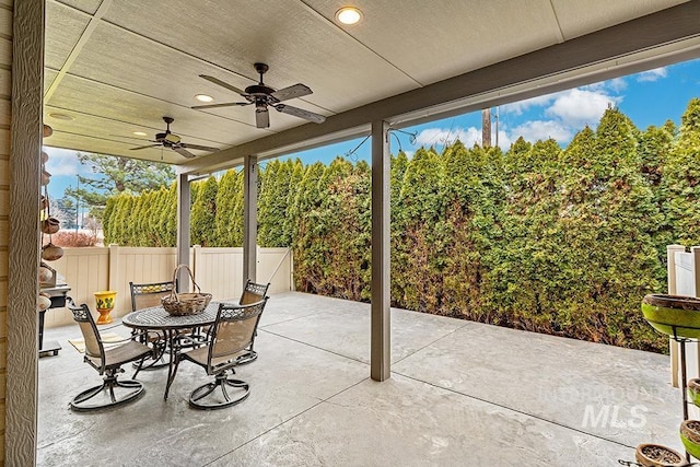 view of patio featuring outdoor dining area, ceiling fan, and fence