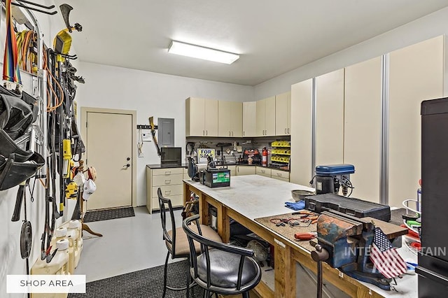 kitchen featuring finished concrete floors, a breakfast bar, electric panel, cream cabinetry, and black fridge