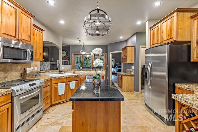 kitchen with recessed lighting, a peninsula, appliances with stainless steel finishes, and a kitchen island