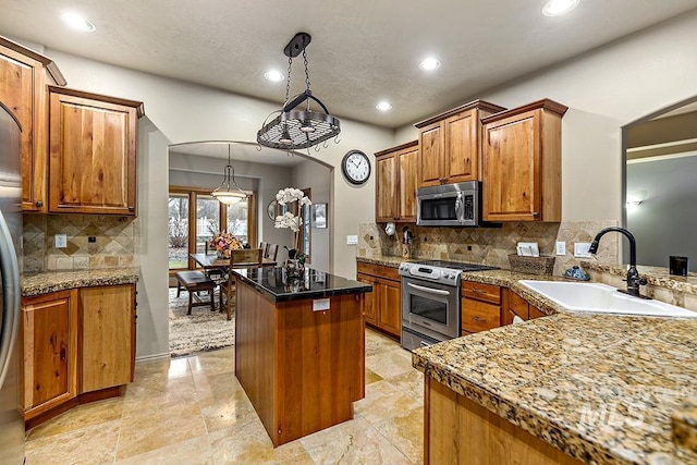 kitchen featuring a center island, a sink, brown cabinetry, decorative backsplash, and stainless steel appliances