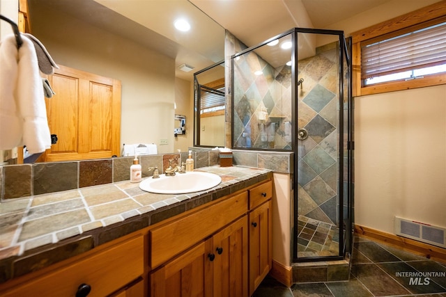 full bath with vanity, baseboards, a shower stall, and visible vents