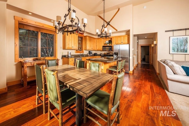 dining area featuring dark wood-style flooring, a high ceiling, a notable chandelier, recessed lighting, and baseboards
