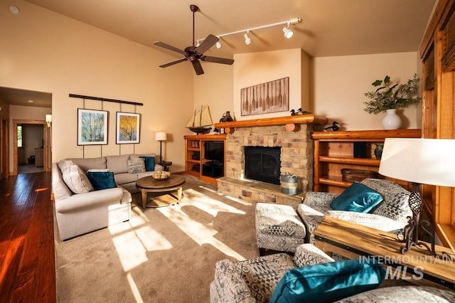 living area featuring a ceiling fan, a glass covered fireplace, track lighting, and wood finished floors